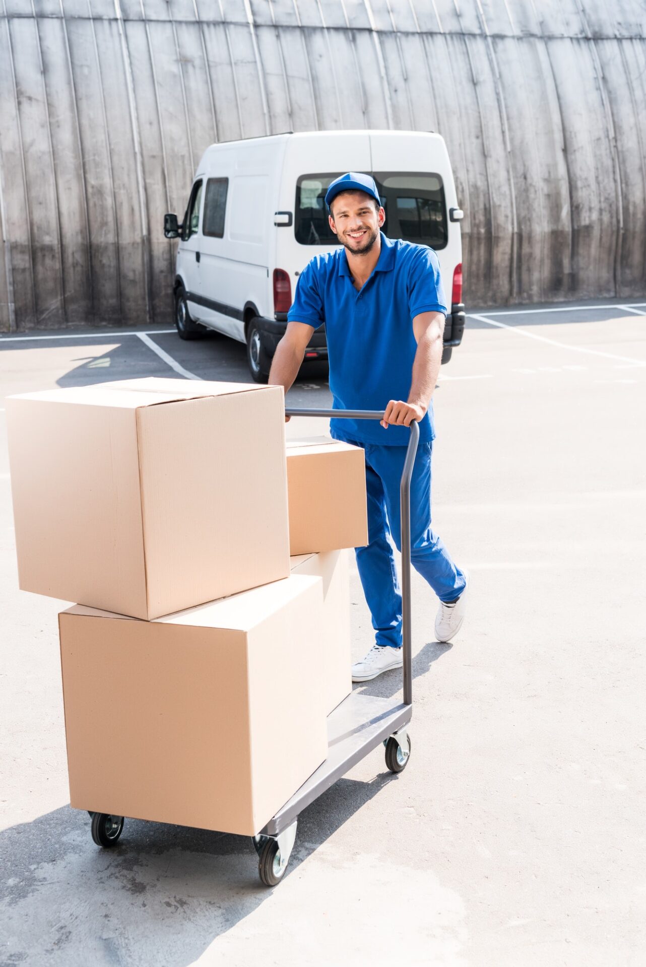 happy delivery man with cardboard boxes on cart