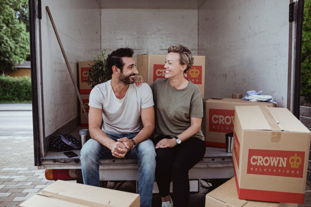 Couple sitting in moving truck surrounded by moving boxes.