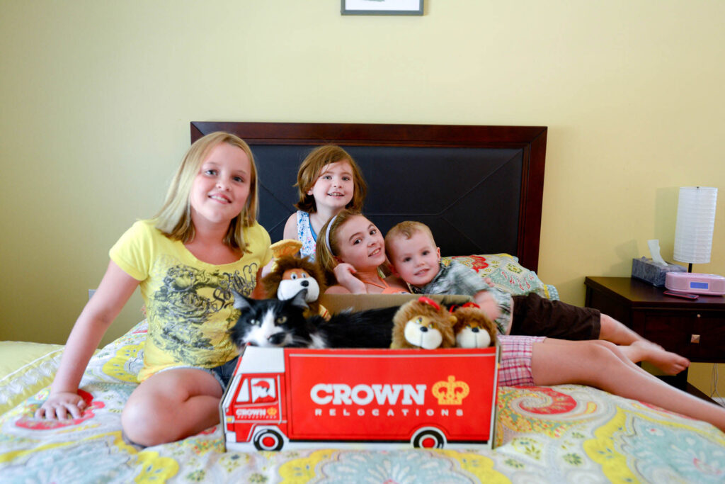 Family on a bed with a Crown Relocations moving box